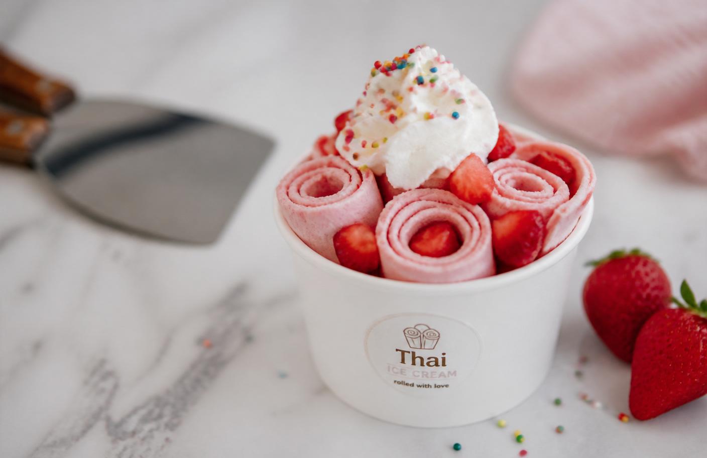 Beautiful rolled Thai ice cream topped with fresh strawberries, whipped cream, and sprinkles